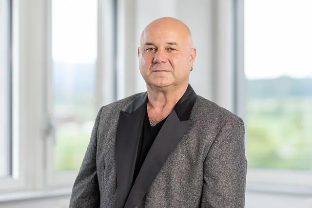 Cosimo Russo in a gray jacket in front of a bright window.