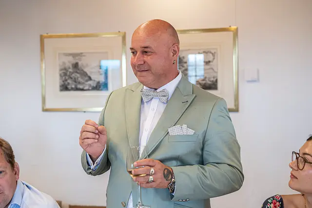 Cosimo Russo, in a light suit, holds a glass and addresses the guests.