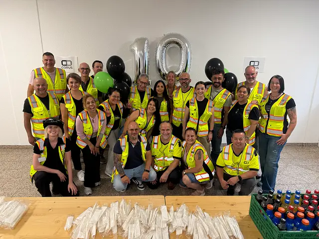 The team in hi-vis vests in front of silver 10 balloons at the shared lunch on the construction site.