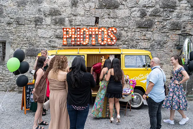 Guests in the yellow photo bus, laughing with bouquets of flowers.