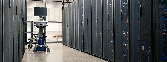 Aisle between server racks in a data center with a bright concrete floor.