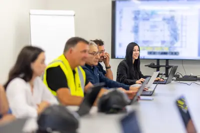 Project team in a coordination meeting, a data-center floor plan on the screen